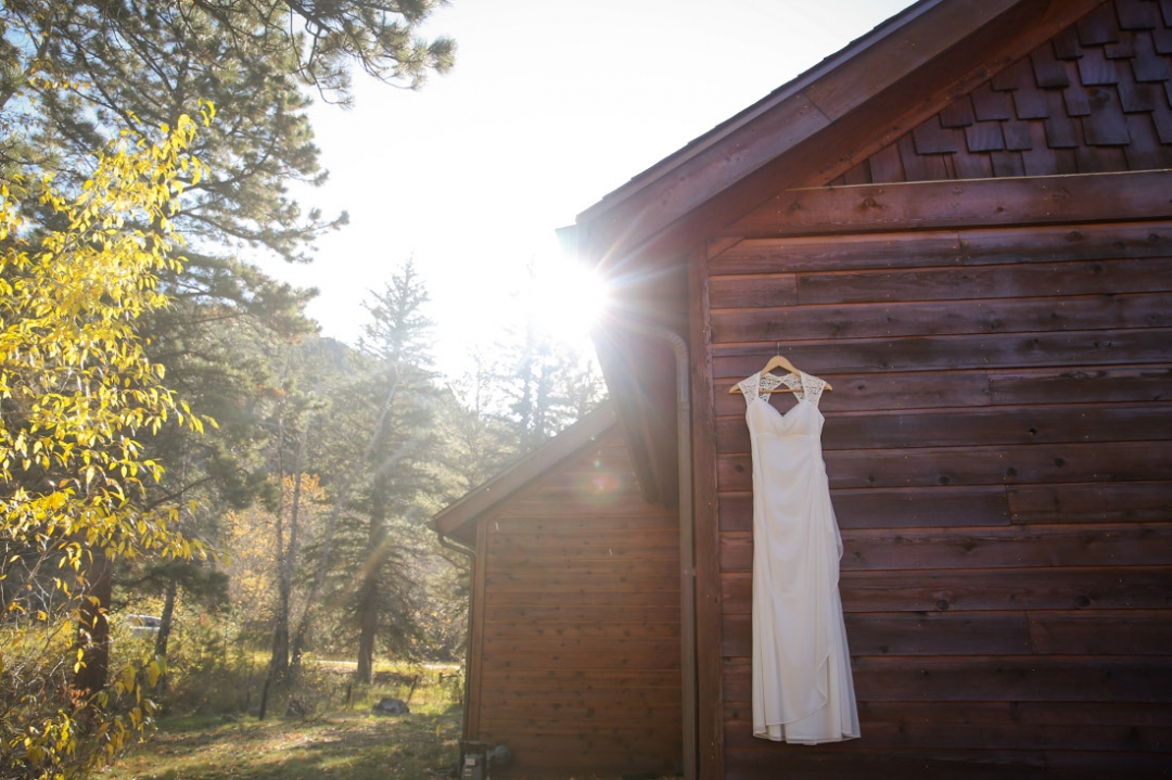 Image of wedding dress on side of cottage in the forest